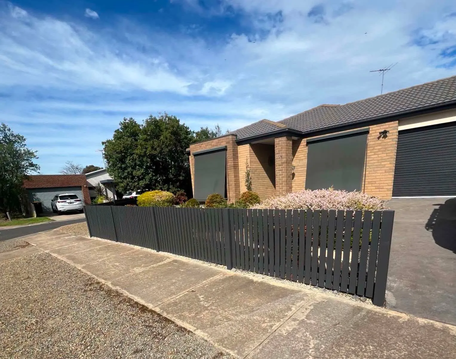 Brick home and garage behind a freshly painted dark fence