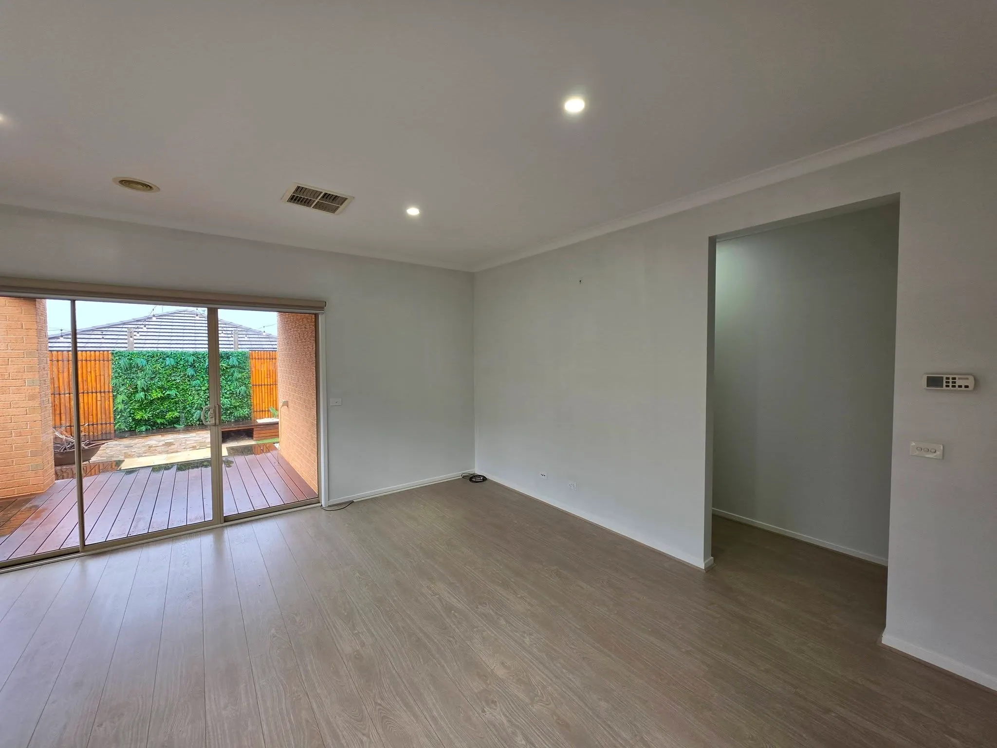 Bright empty living area with light walls and timber-look flooring