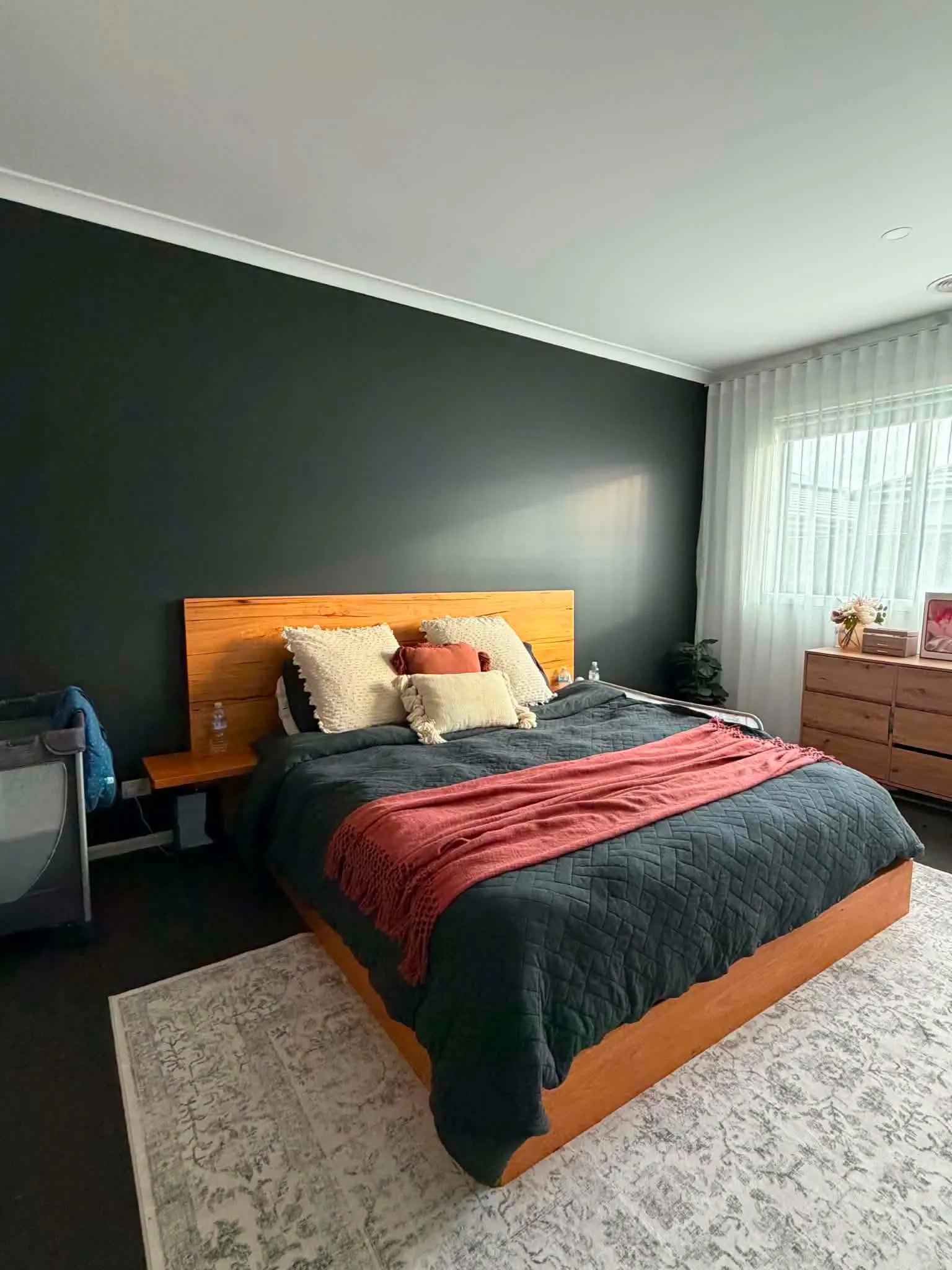 Bedroom with a deep green feature wall and warm timber bed