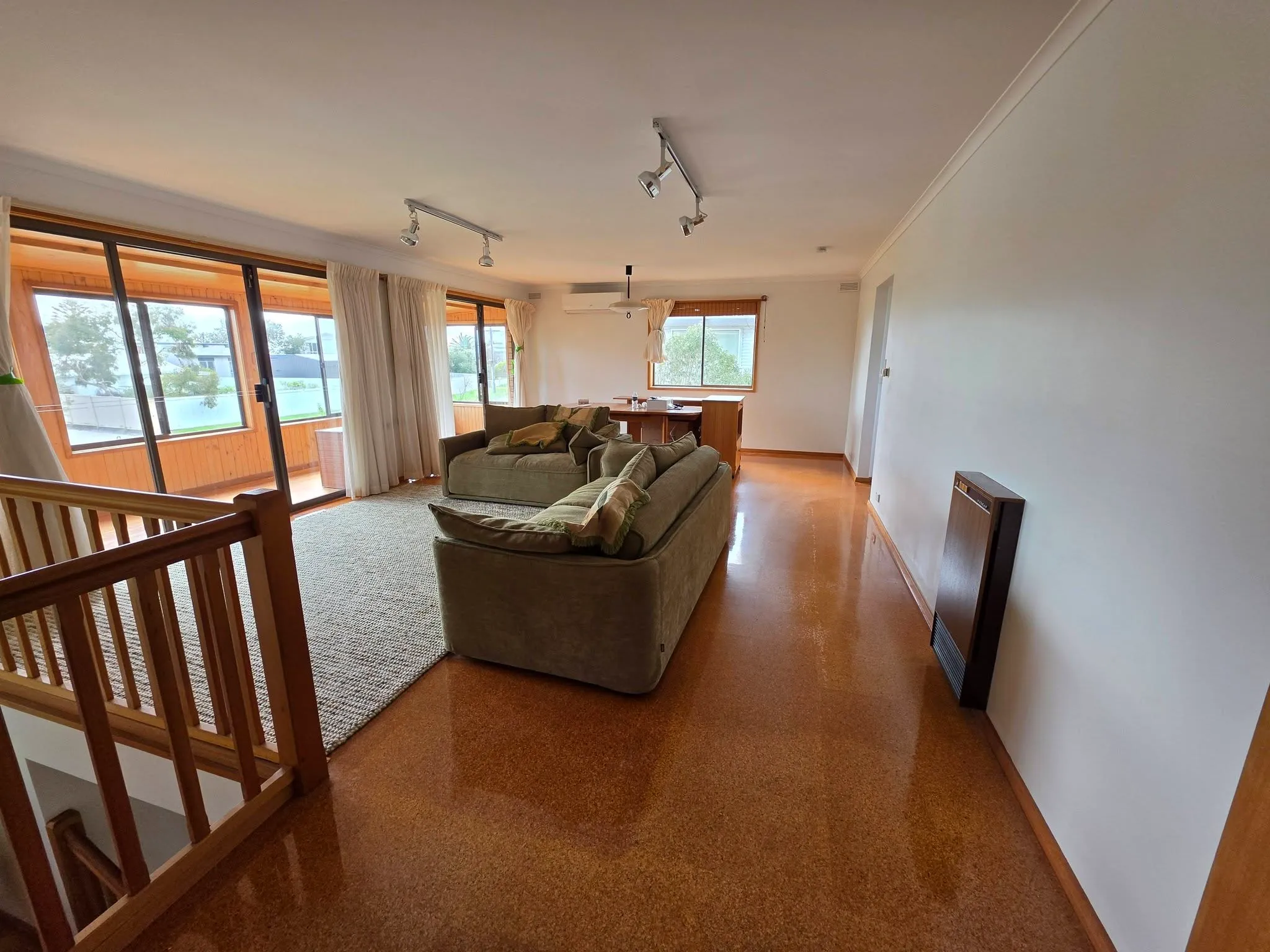 Bright living area with white walls, large windows and timber flooring