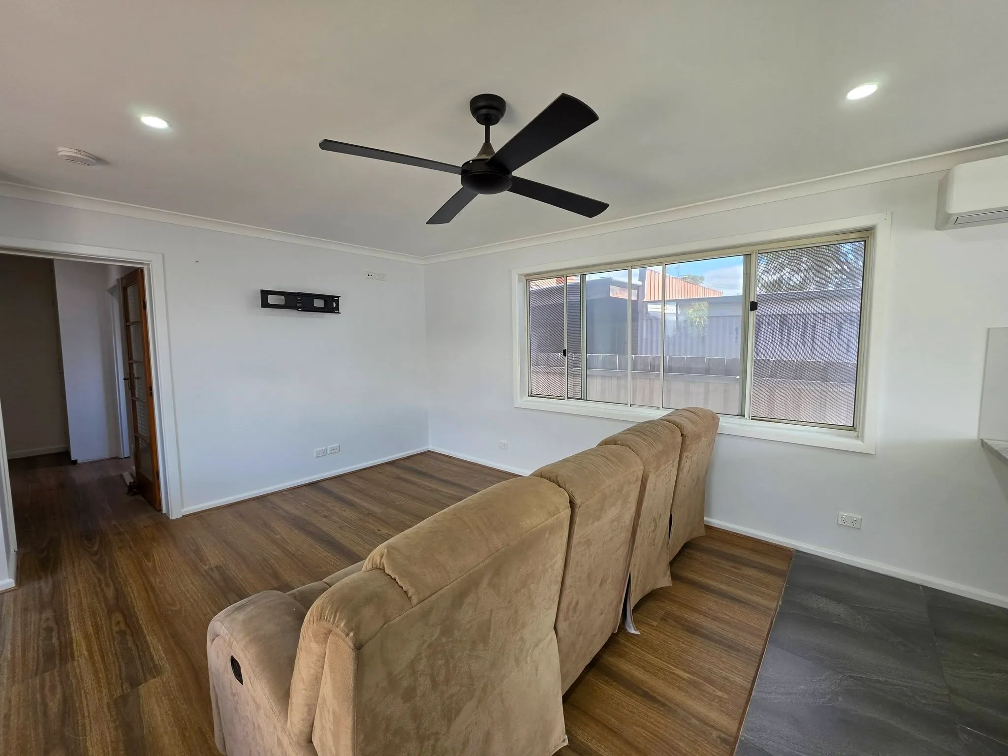 Finished living room with white walls, ceiling fan and timber flooring